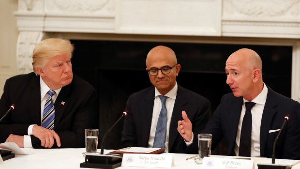 Not much love lost: Donald Trump (with Microsoft CEO Satya Nadella in the centre) listens to Amazon boss Jeff Bezos during an American Technology Council roundtable at the White House last year.