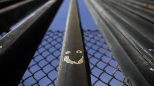 Graffiti adorns metal bars marking the United States border where it meets the Pacific Ocean.