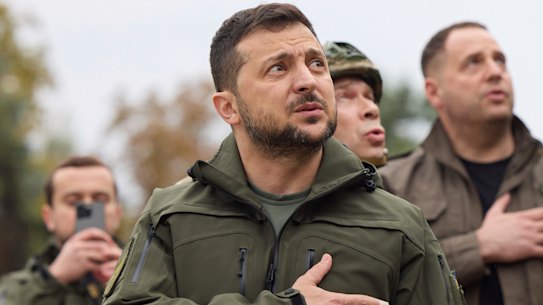 Ukrainian President Volodymyr Zelensky sings the national anthem and raises the Ukraine flag during a visit to the key recaptured town of Izyum.