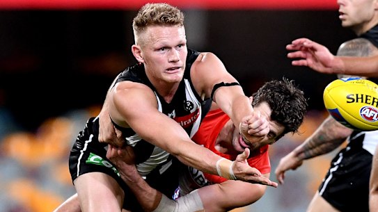 Collingwood star Adam Treloar gets a handball away under pressure from Sydney.