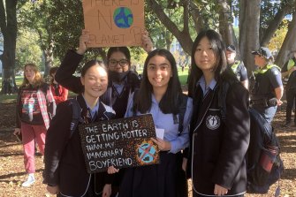 Students from Camberwell Girls Grammar School hold up a hand-written sign at Friday’s protest in Treasury Gardens.