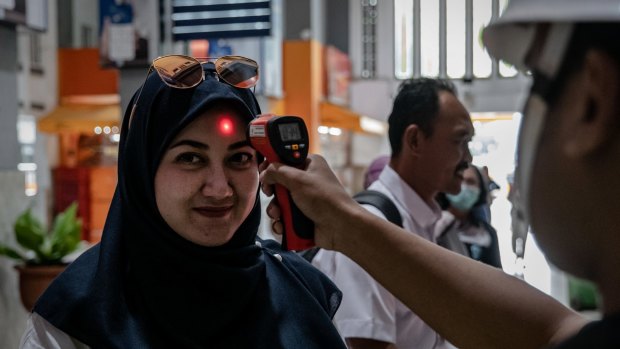 A security guard checks a passenger's body temperature at Tugu train station in Yogyakarta, Indonesia.