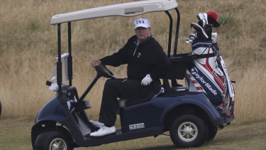 US President Donald Trump drives a golf buggy on his other Scotish golf course, in Turnberry.