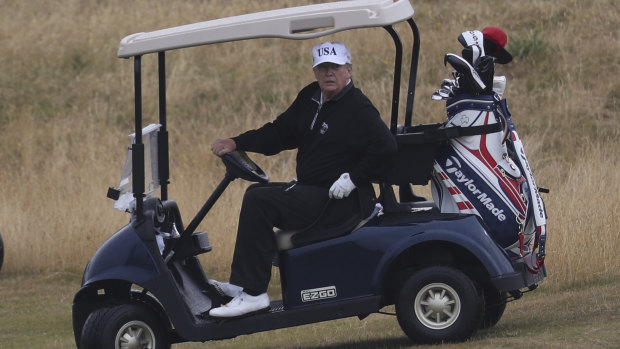 US President Donald Trump drives a golf buggy on his other Scotish golf course, in Turnberry.