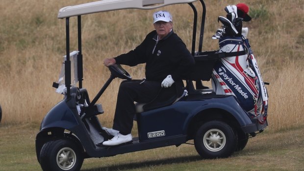 Donald Trump drives a golf buggy on his golf course in Turnberry, Scotland.