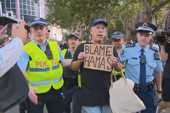 A man carrying a “Blame Hamas” sign was arrested at a rally against the NSW government’s protest laws on Friday.