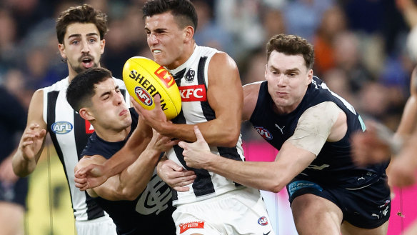 Nick Daicos of the Magpies is tackled by Adam Cerra (left) and Blake Acres of the Blues.
