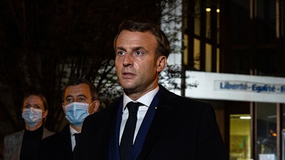 French President Emmanuel Macron, flanked by French Interior Minister Gerald Darmanin, second left, speaks in front of a high school northwest of Paris, after a history teacher was beheaded. 