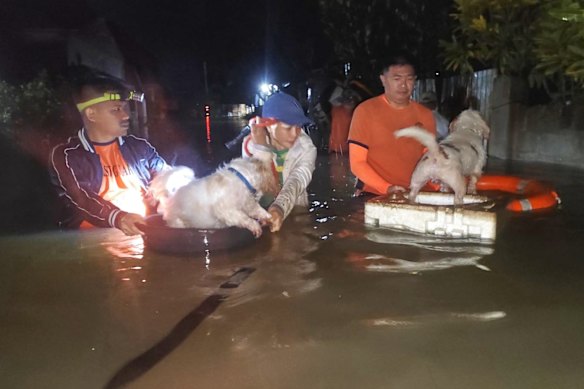 Dalam selebaran yang disediakan oleh Penjaga Pantai Filipina ini, penduduk dan anjing mereka dievakuasi oleh penyelamat ketika banjir naik karena topan bualoi di Filipina minggu lalu.