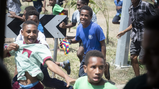 Mobs of children run alongside the Prime Minister's XIII's team bus in Port Moresby on Thursday.