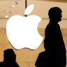 Customers stand beneath an Apple logo at the Apple store in Grand Central station in New York City, July 21, 2015. U.S. stocks opened lower on Tuesday as the dollar remained at a three-month high and ahead of a host of earnings from technology giants including Apple, Microsoft and Yahoo.  REUTERS/Mike Segar