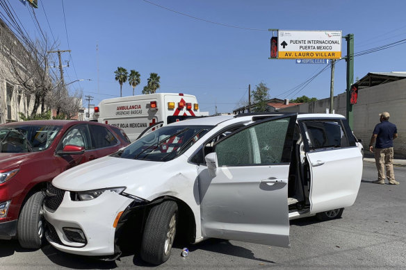 A member of the Mexican security forces stands next to a white minivan with North Carolina plates and several bullet holes at the crime scene.