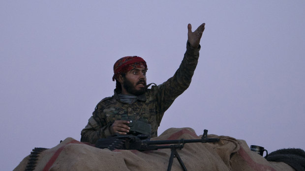 A US-backed Syrian Democratic Forces fighter reacts as an airstrike hits territory still held by Islamic State militants in the desert outside Baghouz, Syria.