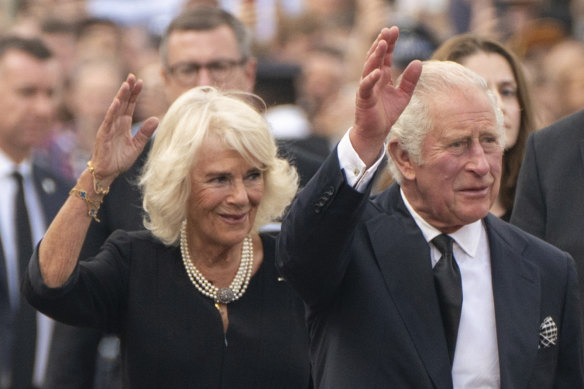 King Charles III, and Camilla, the Queen Consort, wave to the crowd outside Buckingham Palace.