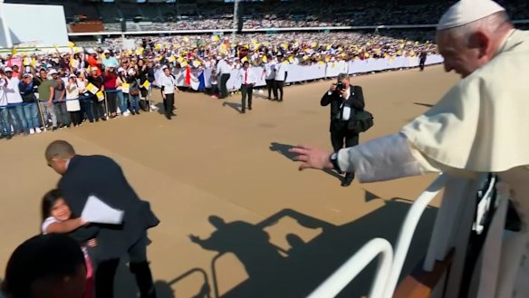 Pope Francis reaches for a letter from a girl who has broken through police barriers in Abu Dhabi.