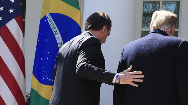 Brazilian President Jair Bolsonaro walks back inside the White House with President Donald Trump.