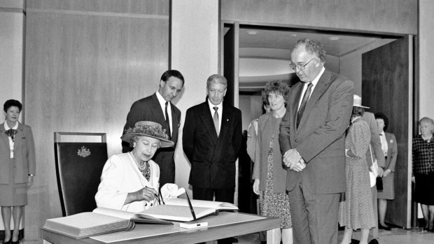 Her Royal Highness Queen Elizabeth II signs the visitors' book at Parliament House, while Prime Minister Paul Keating and Parliament House officials look on, February 1992. 