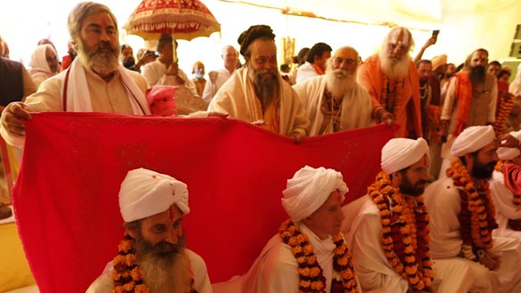 Senior seers offer a sheet of sacred cloth on the newly ordained Mahamandaleshwars of foreign origin as part of the ritual at Sangam.