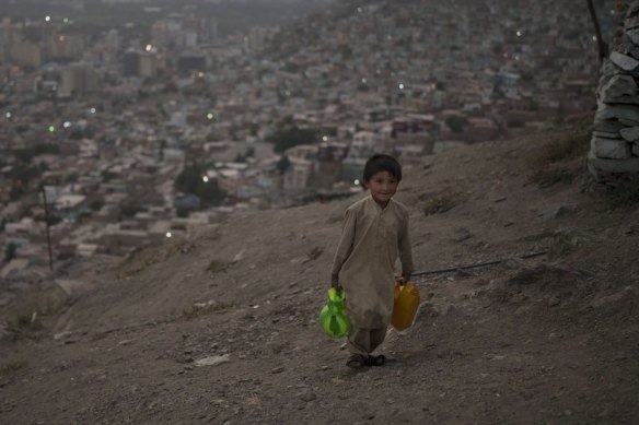 A boy carries water to his home in Kabul, Afghanistan.