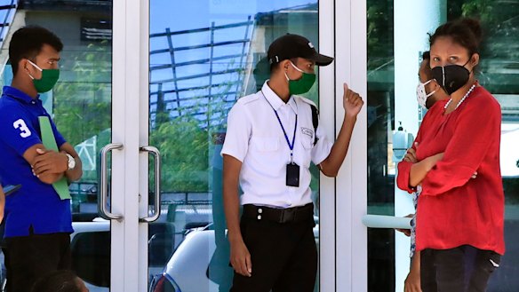 A security guard manages a queue of people waiting to enter a shopping centre in Dili, East Timor. 