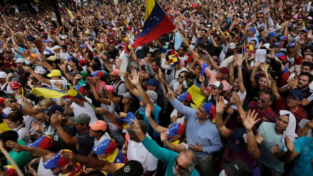 Anti-government protesters hold their hands up during the symbolic swearing-in of Juan Guaido on Wednesday.