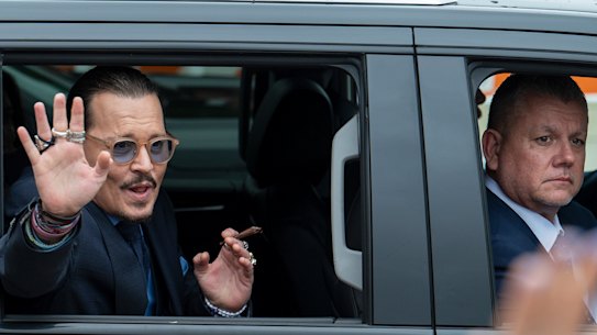 Johnny Depp waves to supporters as he leaves the Fairfax County Courthouse.