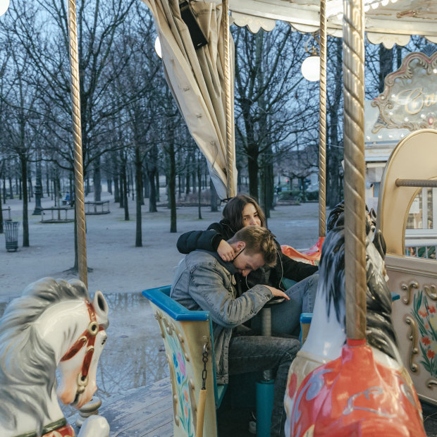A couple ride the carousel, the only open attraction in the Tuileries park, in Paris.