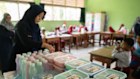 A teacher arranges lunch boxes to be distributed at a school in Jakarta. President Prabowo Subianto promised free school lunches as part of his election campaign, but a deteriorating Indonesian economy has curtailed the program.