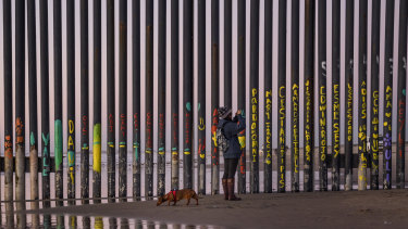 A woman takes a snapshot by the border fence between San Diego, California, and Tijuana, as seen from Mexico. 