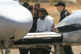 Terence Darrell Kelly, centre, boards a plane after being taken into custody by members of the Special Operations Group at Carnarvon airport on Friday.
