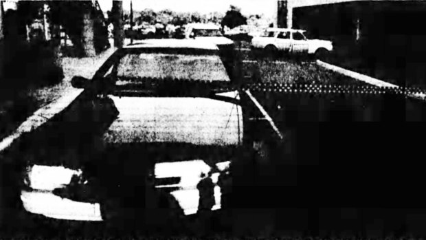 An unmarked cop car bears the scar of a shot fired during the chase. The getaway car is in the background. 