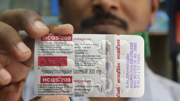 A pharmacist holds a pack of hydroxychloroquine tablets.