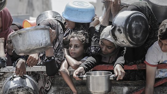 Palestinians wait to collect free food from a charity kitchen in Gaza City.