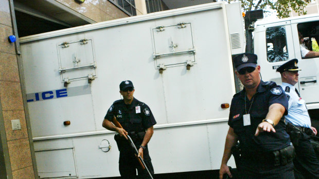 Police guarding the paddy wagon carrying the Pong Su crew members into court