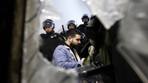 Serbian police officers escort a protester against the autocratic rule of Serbian President Aleksandar Vucic into state-run TV headquarters in Belgrade, Serbia, on Saturday.