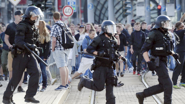 Police officers run during protests in Chemnitz, Germany. 