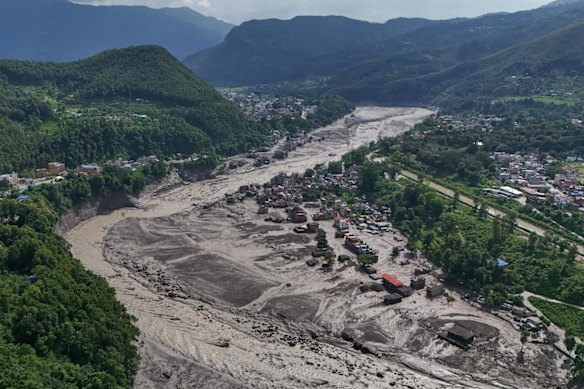 Damaged houses stand precariously near the swollen, debris-choked banks of the Trishuli River after flash floods in Nepal’s Nuwakot district.