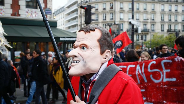 A man wearing a mask of of French President Emmanuel Macron attends a demonstration in Paris this month.