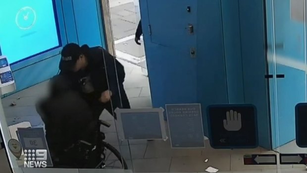 Julian Stewart, in his wheelchair, is robbed by a man at an ANZ branch on George Street, Sydney.