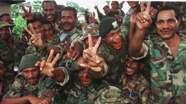 Soldiers of the PNG Defence Forces give the victory sign as they receive news that PM Julius Chan is to step aside.
