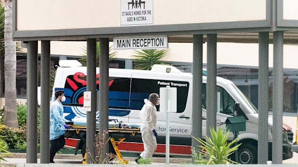 Ambulance workers push a stretcher into the St Basil's aged care facility in Fawkner on Monday.