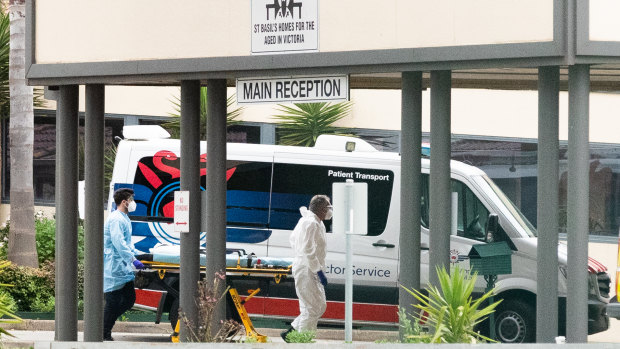 Ambulance workers push a stretcher into the St Basil's aged care facility in Fawkner on Monday.