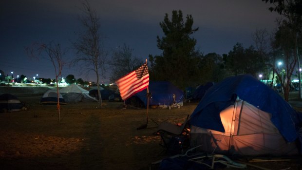 Homeless tents are pitched around an America flag along the Santa Ana River trail in Anaheim, California. 