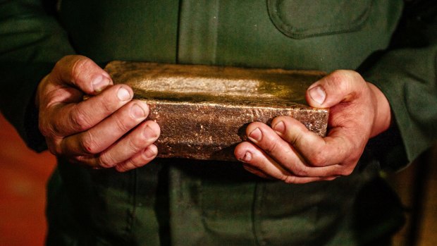 A worker carries a 28-kilogram gold bar.