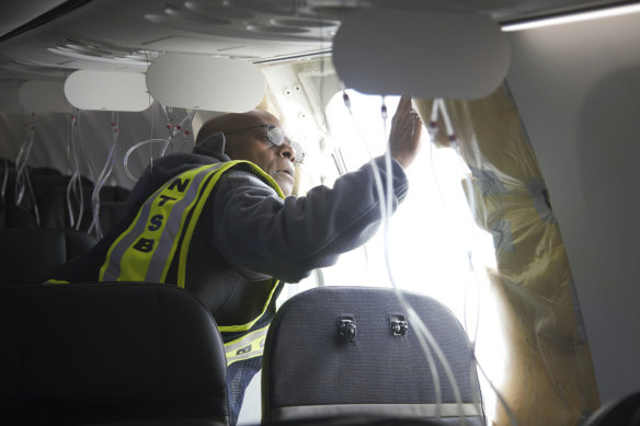 A National Transportation Safety Board  investigator examining the fuselage plug area of Alaska Airlines Flight 1282.