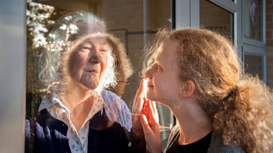 Margaret Wheeler greets her granddaughter Alice through the glass of her aged care facility last year. 