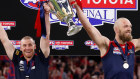 Melbourne coach Simon Goodwin and captain Max Gawn stand euphorically with premiership cup in-hand.