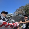 Protesters glue themselves to road during grand final day parade