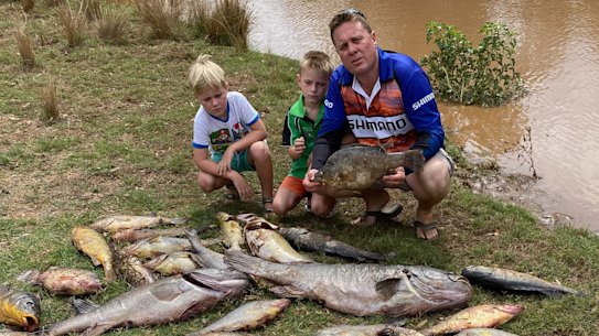 Matt Hansen (right), president of the Inland Waterways group, with his sons, Jack (left) and Cooper, near dead fish pulled from the Macquarie and Bell rivers near Dubbo in recent days.