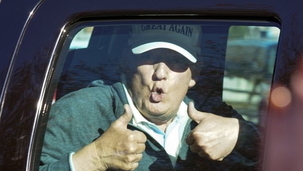 President Donald Trump gives two thumbs up to supporters as he departs after playing golf at the Trump National Golf Club the Sunday after the election.